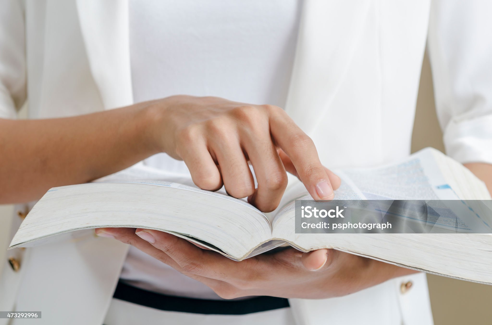 closeup of woman’s hands skimming through a dictionary